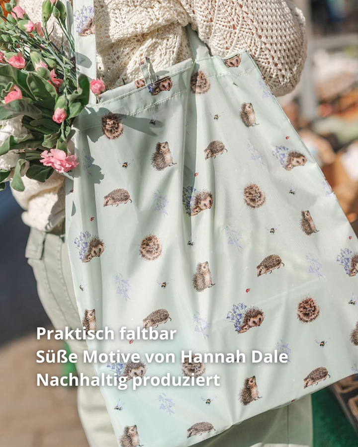 Hellgrüne Igel Einkaufstasche getragen von Wrendale Designs. Das Motiv besteht aus vielen kleinen Igeln Motiven in verschiedenen Posen. Aus der Tasche hängen verschiedene Blumenarten.