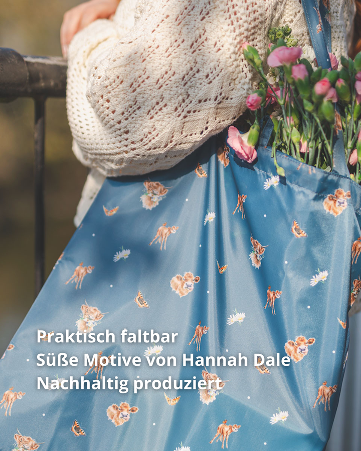 Einkaufstasche Farmyard Friends von Wrendale Designs in Benutzung. Süße Kälbchenmotive von Hannah Dale schmücken gemeinsam mit Schmetterlingen und Blümchen den recycelten Stoff aus Kunstfaser. Ebenfalls im Bild zu lesen sind die Produktvorteile.