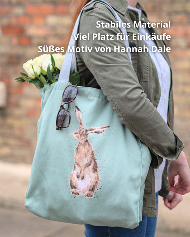 Hellgrüne Hasen-Einkaufstasche von Wrendale Designs getragen von einer Frau. Das Motiv ist ein aufrecht stehender Hase welcher neugierig in die Ferne guckt.  An der Tasche hängt eine Sonnenbrille und es hängen weiße Tulpen raus. 