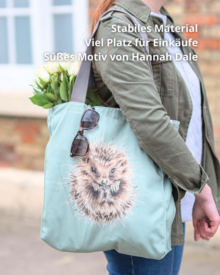 Hellblaue Igel Einkaufstasche mit grauen Griff von Wrendale Designs im Freien Getragen von einer Frau. Das Motiv ist ein eingerollter Igel in der Mitte der Tasche. An der Tasche hängt eine Sonnenbrille und sie ist mit weißen Tulpen gefüllt. 