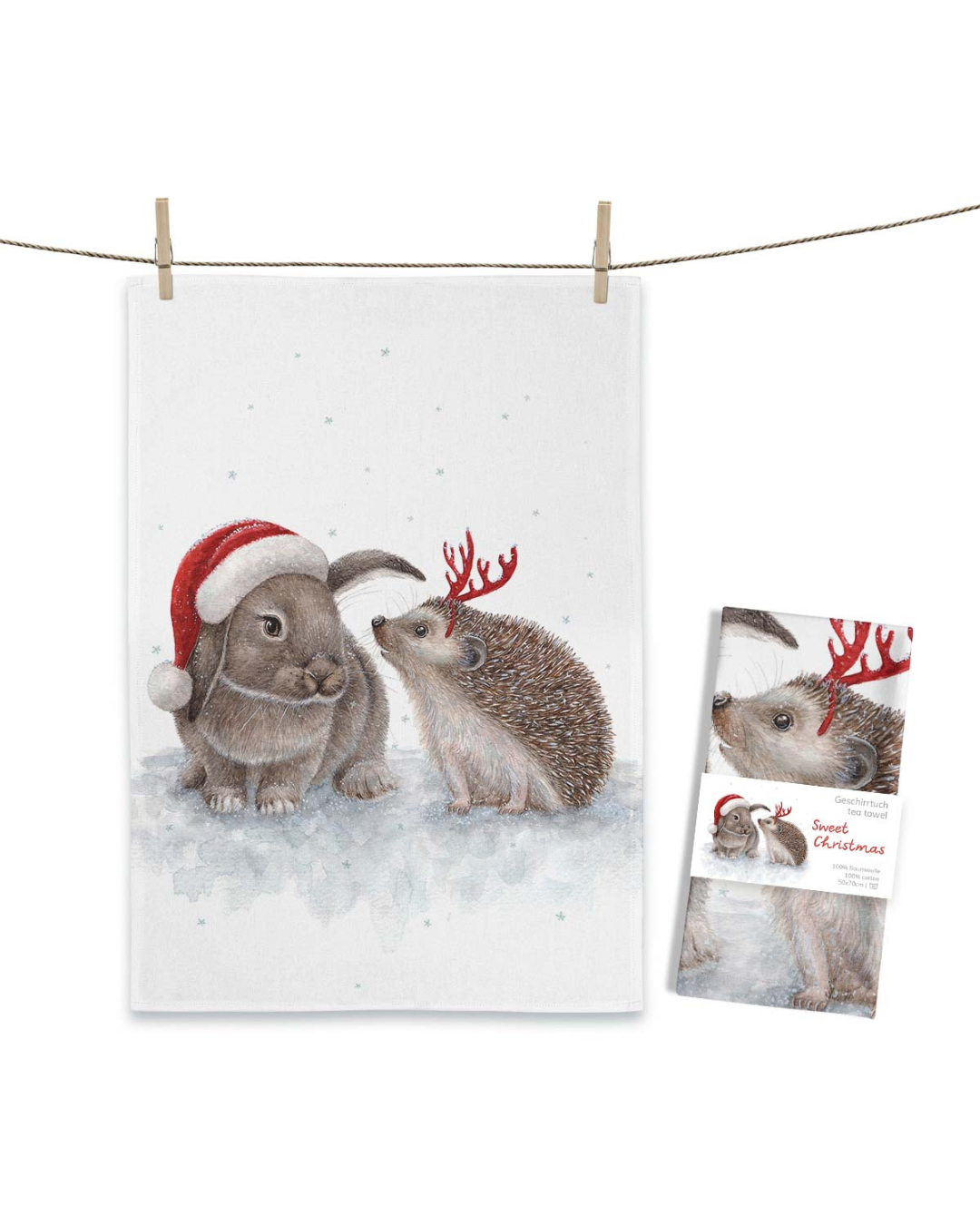 Maluu Geschirrtuch Sweet Christmas, aufgehängt an einer Leine, mit Hase in Weihnachtsmütze und Igel mit roten Geweihhörnchen im Schnee.