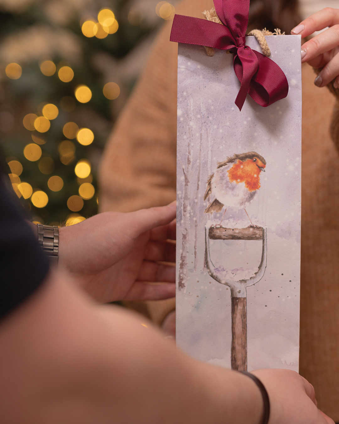 Geschenkübergabe mit Flaschen-Geschenktasche „A Little Red Robin“ von Wrendale Designs.