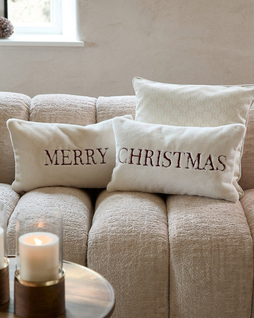 Merry- und Christmas-Kissen von Rivièra Maison nebeneinander auf gemütlichem Sofa