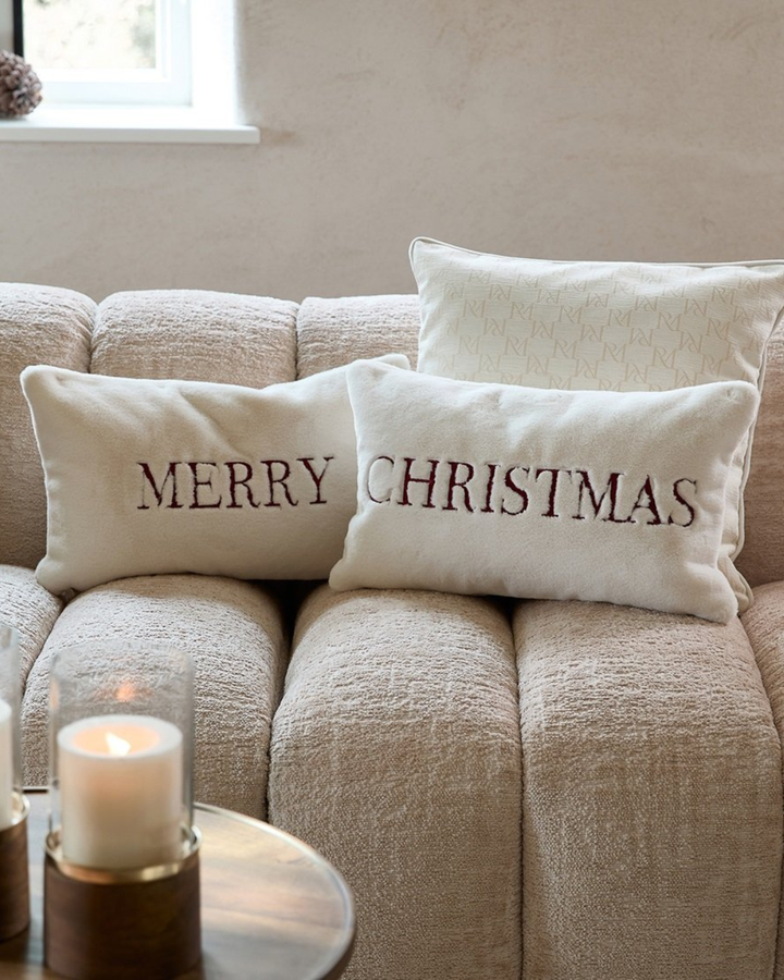 Merry- und Christmas-Kissen von Rivièra Maison nebeneinander auf gemütlichem Sofa