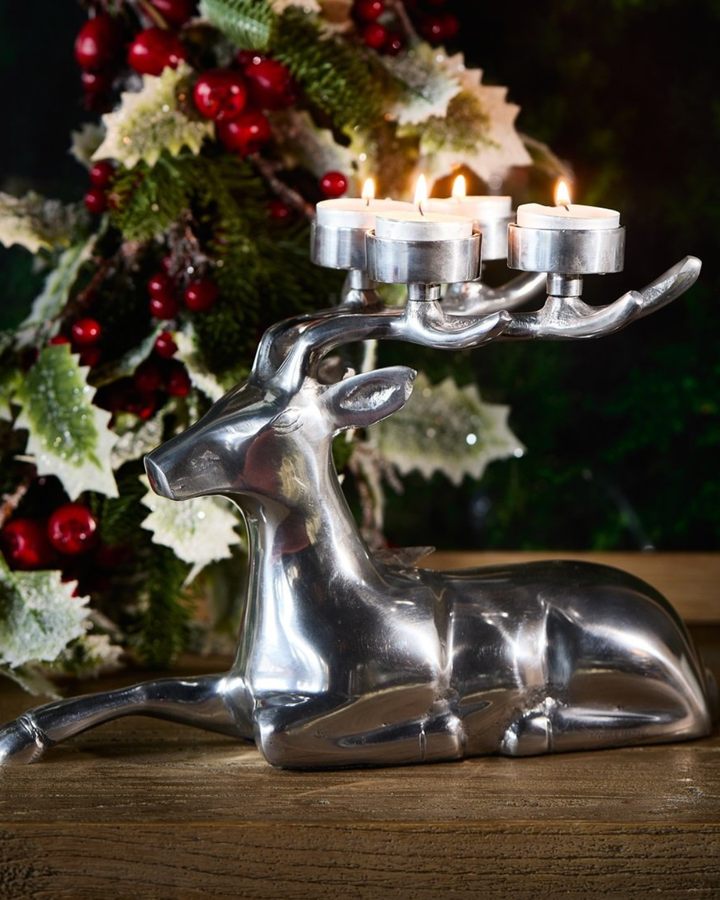 „Dekorierter Reindeer Candle Holder mit brennenden Teelichtern vor weihnachtlicher Kulisse“