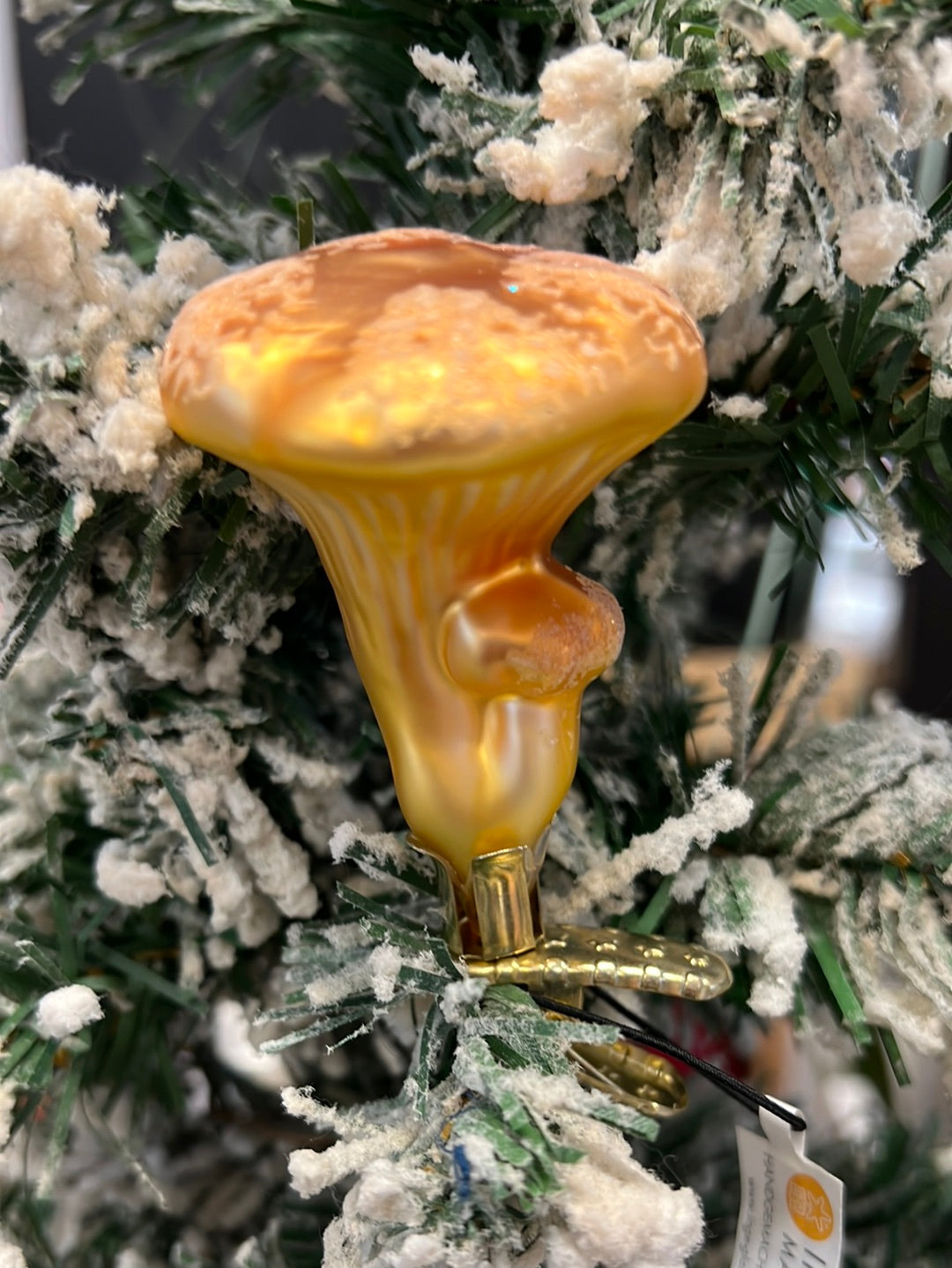Handgefertigtes Pfifferling Ornament von Inge Glas hängend in einem winterlichen Tannenbaum.