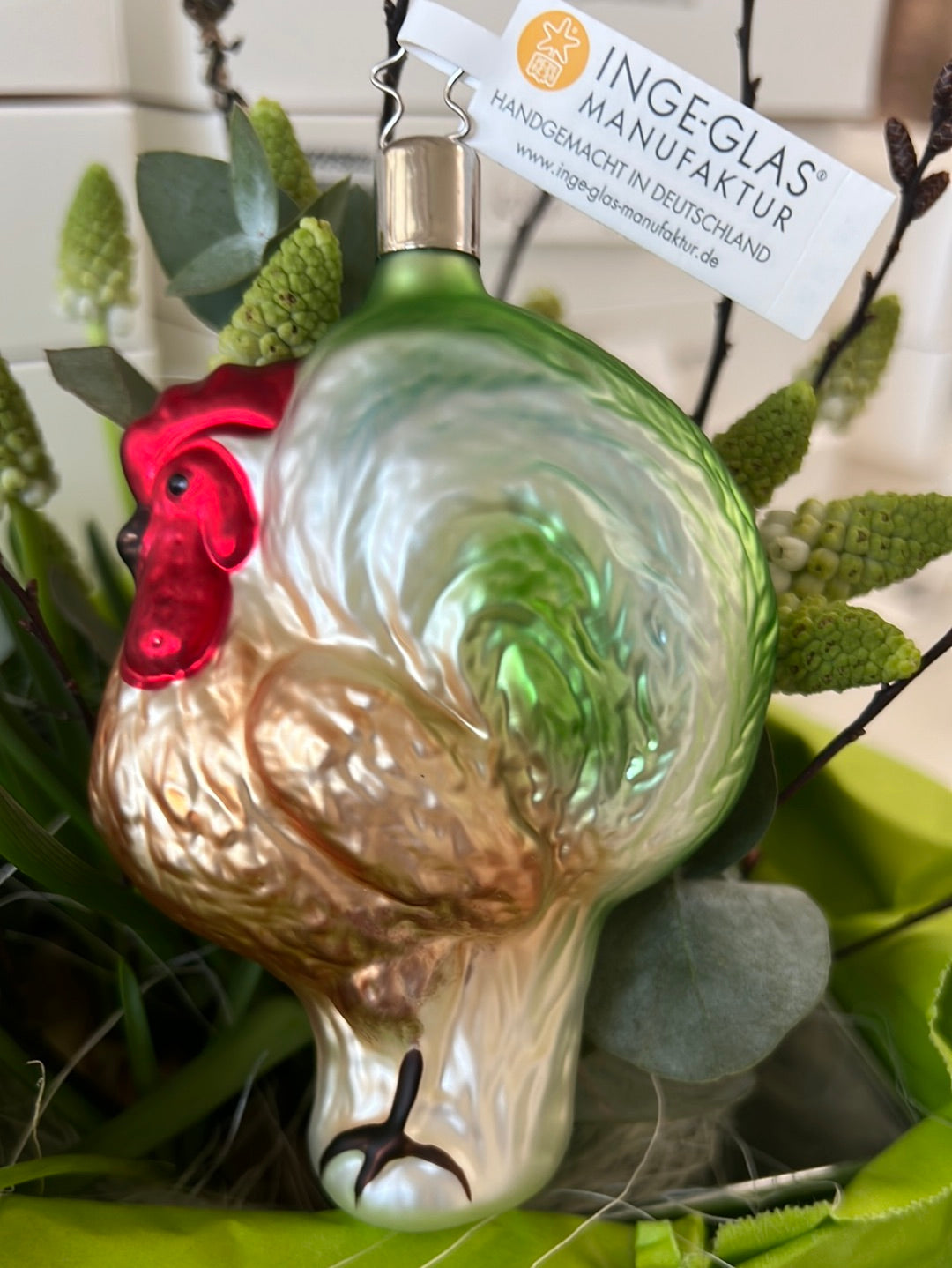 Handgefertigter stolzer Hahn von Inge Glas mit braun-weiß-grünem Gefieder und rotem Kamm.